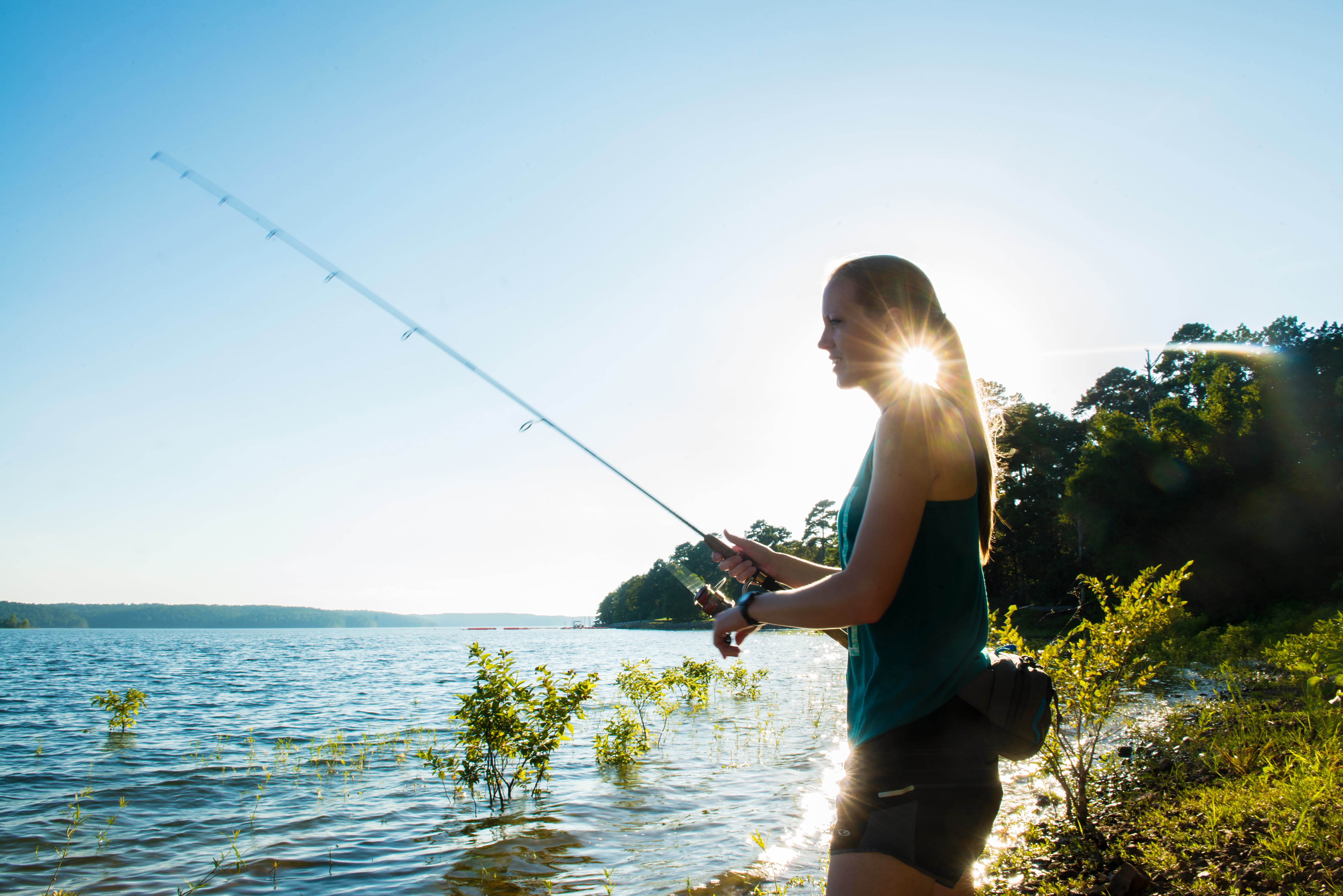 Young woman fishing from the shore of DeGray Lake 